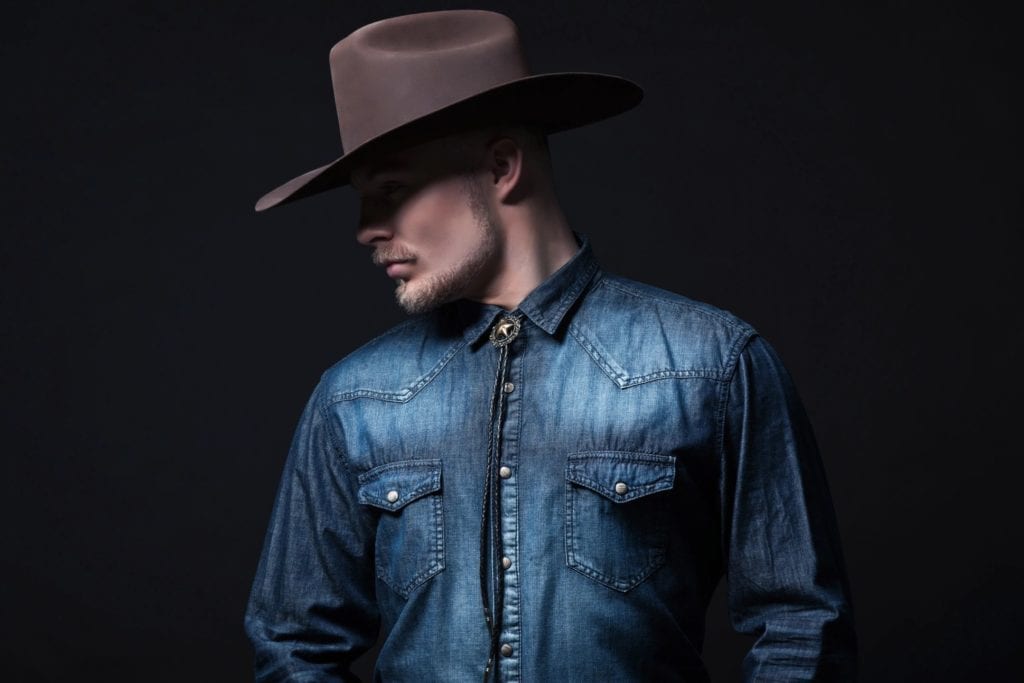 Man wearing a leather jacket and a cowboy hat